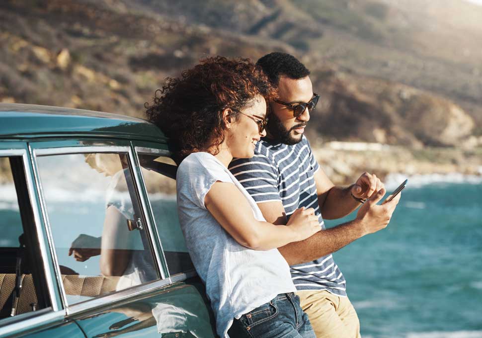 Couple leaning on car using phone