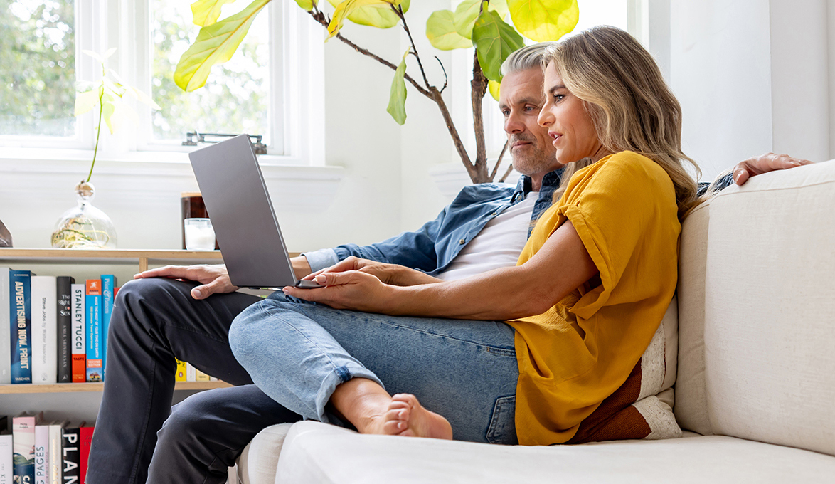 Couple on the couch using a mortgage closing cost calculator.