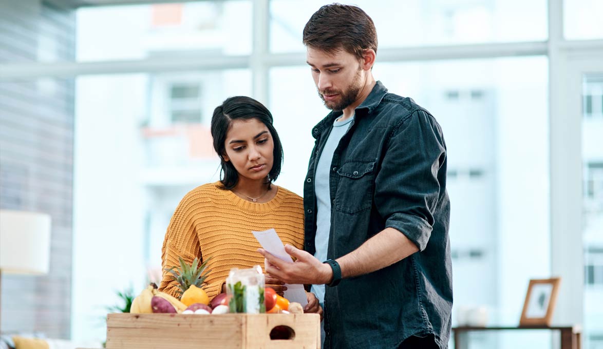 couple looking at rising prices of food on grocery receipt