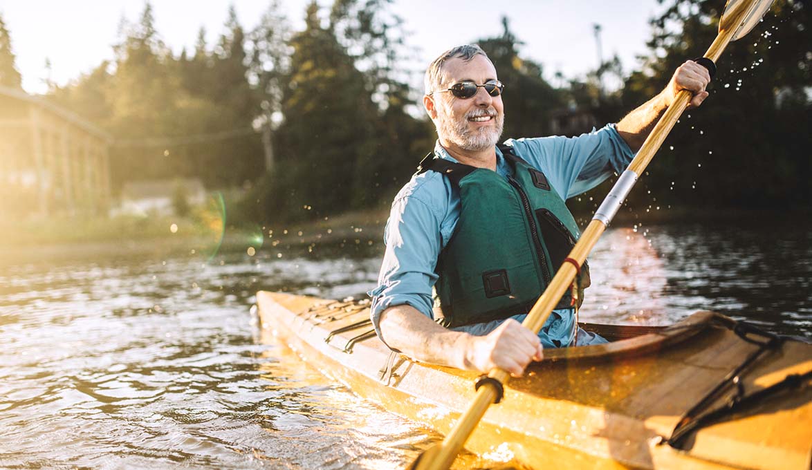 man enjoying kayaking on a lake during retirement