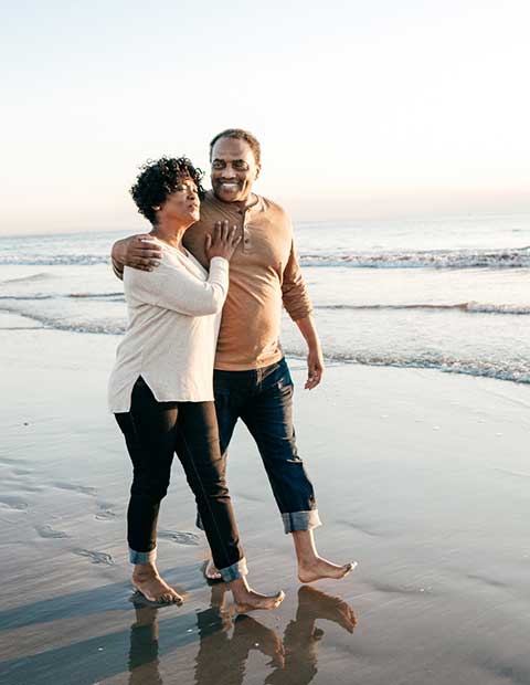 promo image for senior couple enjoying beach walk during retirement